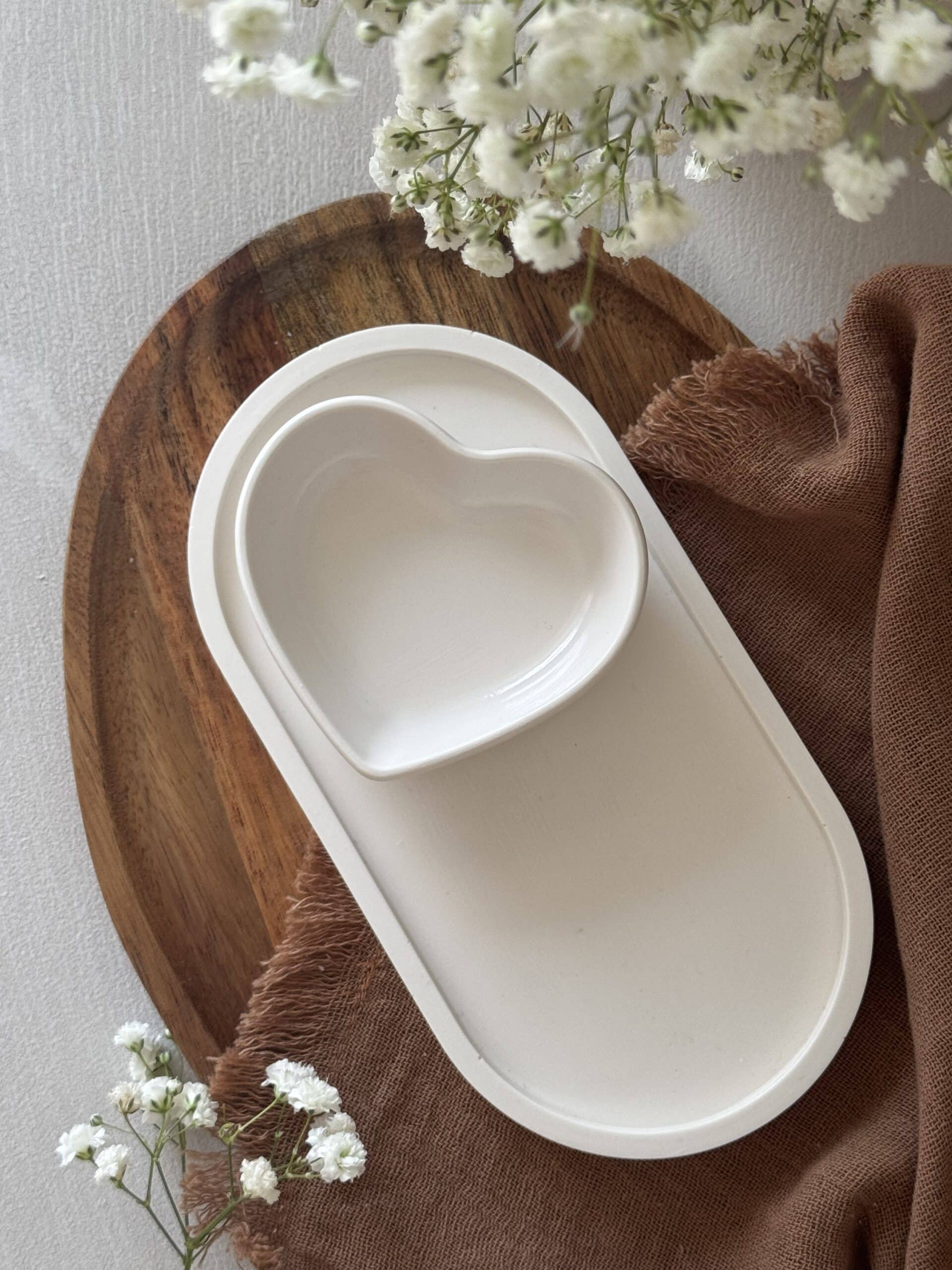 Bandeja decorativa ovalada de resina ecológica en color natural con bandeja corazón blanca sobre una base de madera